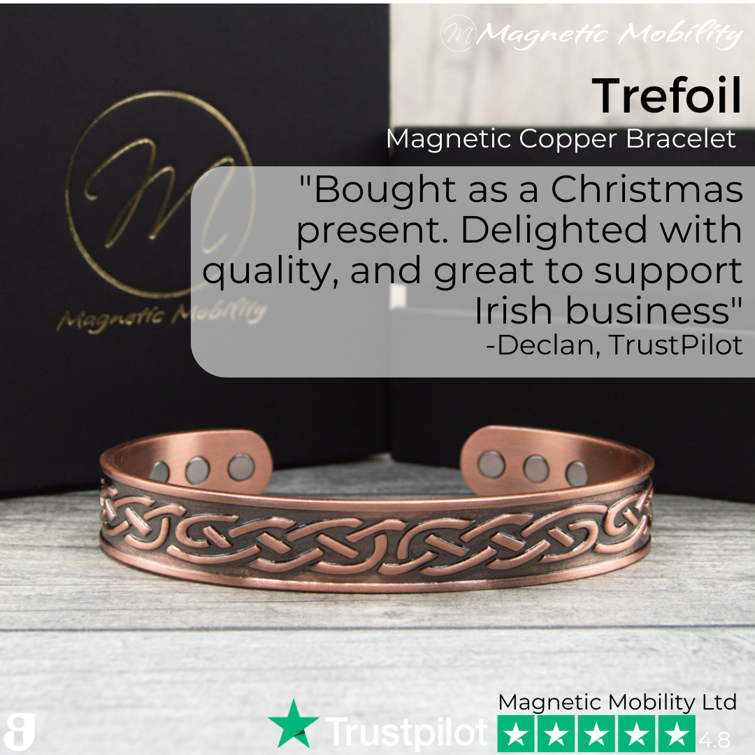 45 degree view of the Trefoil Copper bracelet from Magnetic Mobility. A copper bracelet with a celtic design. The bracelet is shown on a wooden surface with a black gift box behind it. Perfect for people with arthritis and back pain. 99% pure copper. Customer review written on the image from Trustpilot stating "Bought as a Christmas present. Delighted with the quality and great to support an Irish business".