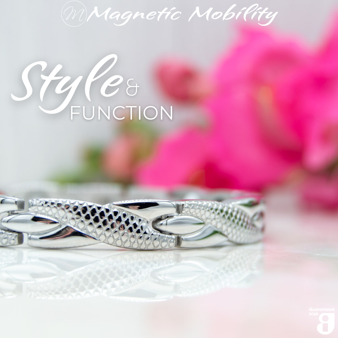 45 degree view of the Snapdragon Star 4in1 magnetic bracelet by Magnetic Mobility. Shown on a reflective surface with pink flowers in the background. The text says "Style and Function" and "Designed for people with arthritis, back pain, fibromyalgia, joint and muscle pain, menopause symptoms, migraine and more". 