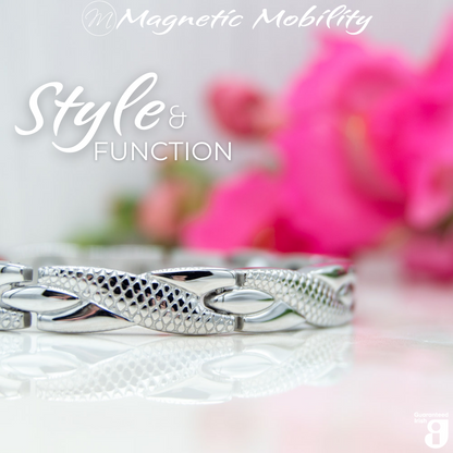 45 degree view of the Snapdragon Star 4in1 magnetic bracelet by Magnetic Mobility. Shown on a reflective surface with pink flowers in the background. The text says "Style and Function" and "Designed for people with arthritis, back pain, fibromyalgia, joint and muscle pain, menopause symptoms, migraine and more". 