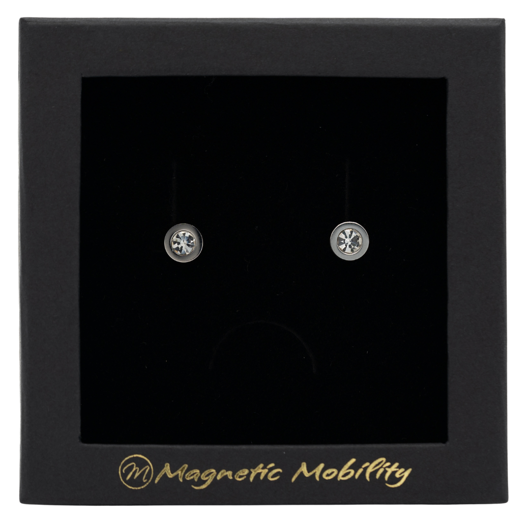 Magnetic Mobility April Birthstone Stud Earrings featuring clear Swarovski crystals, elegantly presented in a black box with Magnetic Mobility branding. These magnetic back earrings offer stylish pain relief.