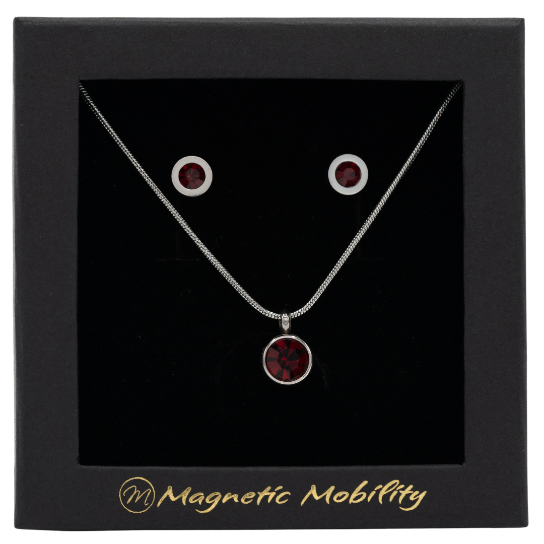 July Magnetic Mobility Birthstone Gift Set featuring a Magnetic Necklace and Stud Earrings featuring ruby red Swarovski crystals, elegantly presented in a black box with Magnetic Mobility branding. These magnetic back earrings offer stylish pain relief.