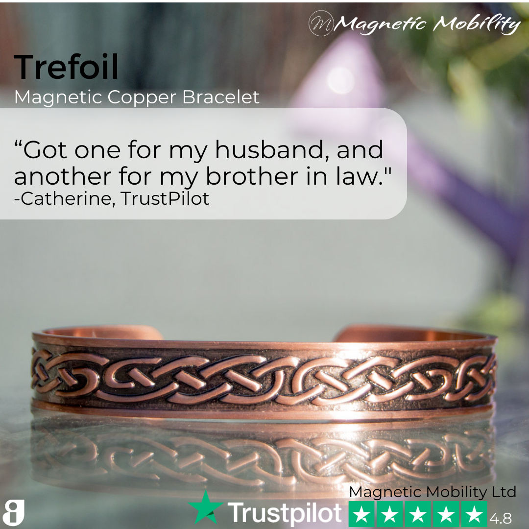 view of the Trefoil Copper bracelet from Magnetic Mobility. A copper bracelet with a celtic design. The bracelet is shown on a reflective surface in a garden. Perfect for people with arthritis and back pain. 99% pure copper. Customer review written on the image from Trustpilot stating "Got one for my husband and another for my brother in law". 